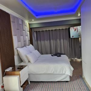 a bedroom with a large bed with a blue ceiling at Cozy & Modern Apartment -Self Catering in Pretoria +11 photos