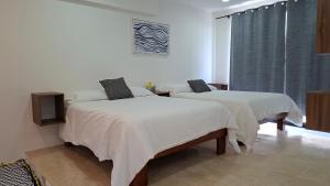 a bedroom with two beds with white sheets at Villas Boutique Casa Ricarda in Aticama