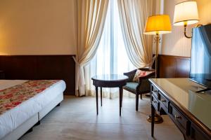 a hotel room with a bed and a table and a television at Grand Hotel Bastiani in Grosseto