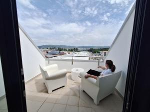 a woman sitting in a chair on a balcony with a laptop at Hotel Spa Odeón in Ferrol