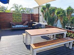 a wooden deck with a table and a bench at The Deck in Jeffreys Bay