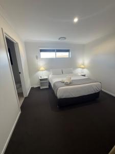 a white bedroom with a bed and a window at The Holiday Home Griffith in Griffith