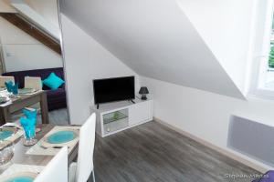 un salon blanc avec une table et une télévision dans l'établissement Le Sancy, à Le Mont-Dore 13 autres photos