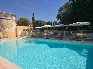 a large swimming pool with chairs and umbrellas at Le Mas des Quintrands Manosque - Motel de charme in Manosque