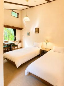 two beds in a room with a table and a desk at Komorebi Myoko Lodge in Myoko