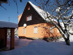 a house with a black roof in the snow at Apartment Na Pražské Vrchlabí in Vrchlabí