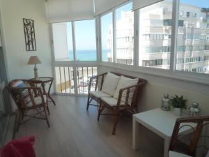 een woonkamer met stoelen en een tafel en ramen bij Casa Mar in Costa da Caparica