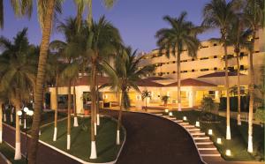 a hotel with palm trees in front of a building at Dreams Huatulco Resort & Spa in Santa Cruz Huatulco