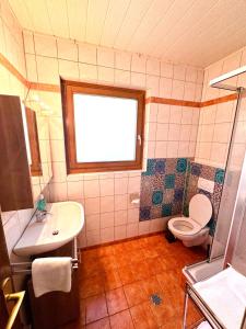 a bathroom with a toilet and a sink and a window at Alpenhof M&E in Bad Kleinkirchheim +20 photos