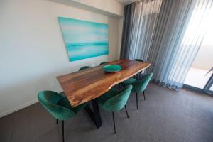 a dining room with a wooden table and green chairs at Terminus Apartment Hotel, an Ascend Collection Hotel in Newcastle