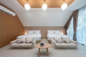 two beds in a room with two couches and a table at Plerntaan HoReCa in Ban Khlong Kum