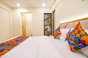 a bedroom with a large white bed with colorful pillows at Via 24x7 in Mumbai