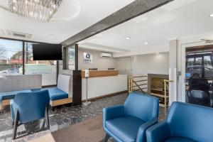 a waiting room with blue chairs and a tv at Quality Inn JFK Airport Rockaway Blvd in Queens