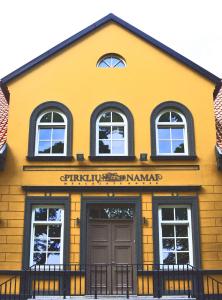 um edifício amarelo com uma porta e janelas em Guest House Pirklių Namai em Klaipeda