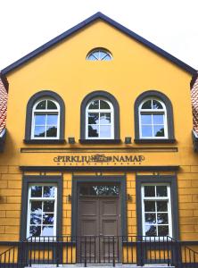 a yellow building with a door and windows at Guest House Pirklių Namai in Klaipėda