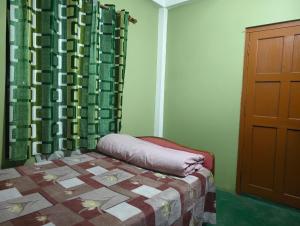 a bedroom with a bed and a curtain and a door at itynnad homestay in Shillong