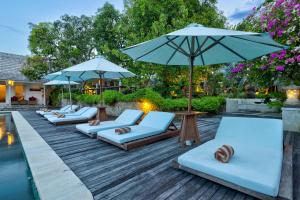 a row of lounge chairs with umbrellas and a pool at Villa Olala Penida in Nusa Penida
