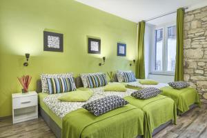 sypialnia z 2 łóżkami z zieloną pościelą i poduszkami w obiekcie Top Center Rooms & Studio w Puli