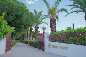 a driveway with palm trees and a pink fence at Villa Pami in Almiros Beach