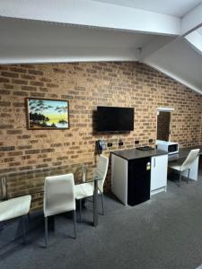 a room with a table and chairs and a tv on a brick wall at Clock Tower Motor Inn in Coonabarabran