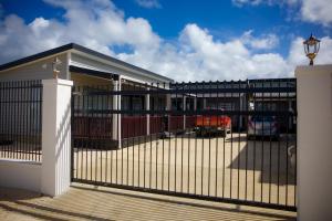 a fence in front of a building with a parking lot at Taisia & Liku Homes in Nuku‘alofa