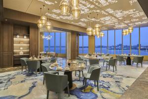 a dining room with tables and chairs and large windows at Hyatt Regency Shanghai Pudong Lingang in Zhenghai
