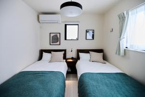 two twin beds in a room with a window at White Breeze House in Ginowan +38 photos