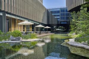 a river with tables and umbrellas next to a building at Hyatt Regency Shanghai Pudong Lingang in Zhenghai