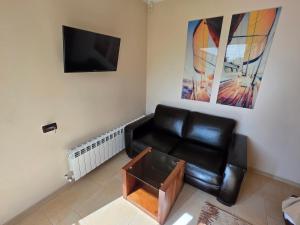 a living room with a black leather couch and a tv at Casa de la Mare in Eforie Sud