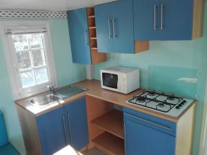 a small kitchen with blue cabinets and a microwave at Camping Cubillas in Cubillas de Santa Marta