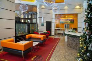 a lobby with orange furniture and a christmas tree at Grand Voyage Hotel in Almaty