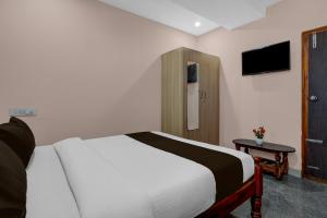a bedroom with a white bed and a tv at Hotel O Chikkabanavara Lakeview Bangalore Formerly Bvk Residency in Bangalore