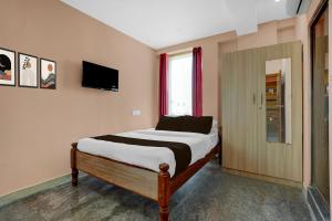 a bedroom with a bed and a tv on the wall at Hotel O Chikkabanavara Lakeview Bangalore Formerly Bvk Residency in Bangalore +25 photos