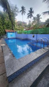 a large swimming pool with blue tiles and palm trees at Casa Viora in Calangute