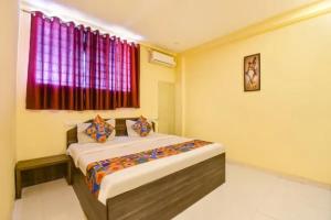 a bedroom with a bed and a window with red curtains at FabHotel Blue Inn I in Vagholi