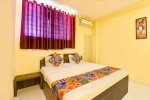 a bedroom with a bed in a room with a window at FabHotel Blue Inn I in Vagholi