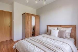 a bedroom with a large bed and a wooden cabinet at Apartament Piastowska Elite in Gdańsk