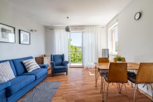 a living room with a blue couch and a table and chairs at Apartament Piastowska Elite in Gdańsk