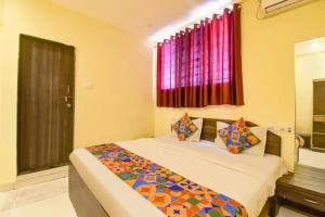 a bedroom with a bed and a window with red curtains at FabHotel Blue Inn I in Vagholi