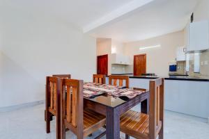 a kitchen with a wooden table and some chairs at Super Collection O Technopark Phase 1 Formerly Snehalayam in Trivandrum