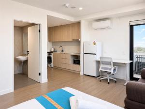 a kitchen with a white refrigerator and a chair in a room at Granville Studio Ensuite toilet and kitchen in Clyde