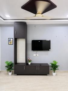 a living room with a tv on a wall with two plants at SV Serenity Homestays in Gachibowli