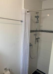a shower with a white shower curtain in a bathroom at Häuschen mit Gartenblick in Idstein +5 photos