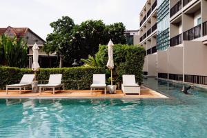 a swimming pool with chairs and umbrellas in a hotel at The Melody Phuket Kata Beach in Kata Beach +21 photos