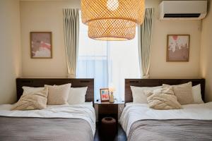 a bedroom with two beds and a chandelier at Black Grove House in Ginowan