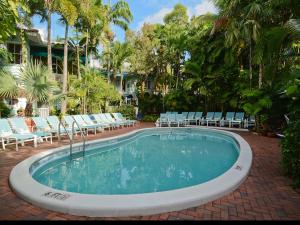 a large swimming pool with chairs and trees at Pineapple Point Guesthouse & Resort - Gay Men's Resort in Fort Lauderdale