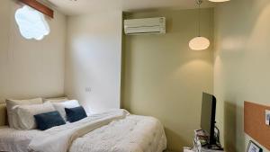 a bedroom with a bed with blue pillows and a television at Halo Bonjour Perch in Ban Chuang