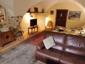 a living room with a leather couch and a television at le logis des Sieyes in Crévoux