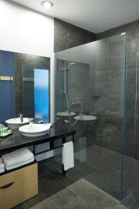 W łazience znajduje się szklana kabina prysznicowa i umywalka. w obiekcie Le Dauphin Montréal Centre-Ville w Montrealu