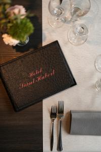ein Tisch mit einer schwarzen Serviette und Gabeln darauf in der Unterkunft Hotel Saint-Hubert in Malmedy + 28 Fotos